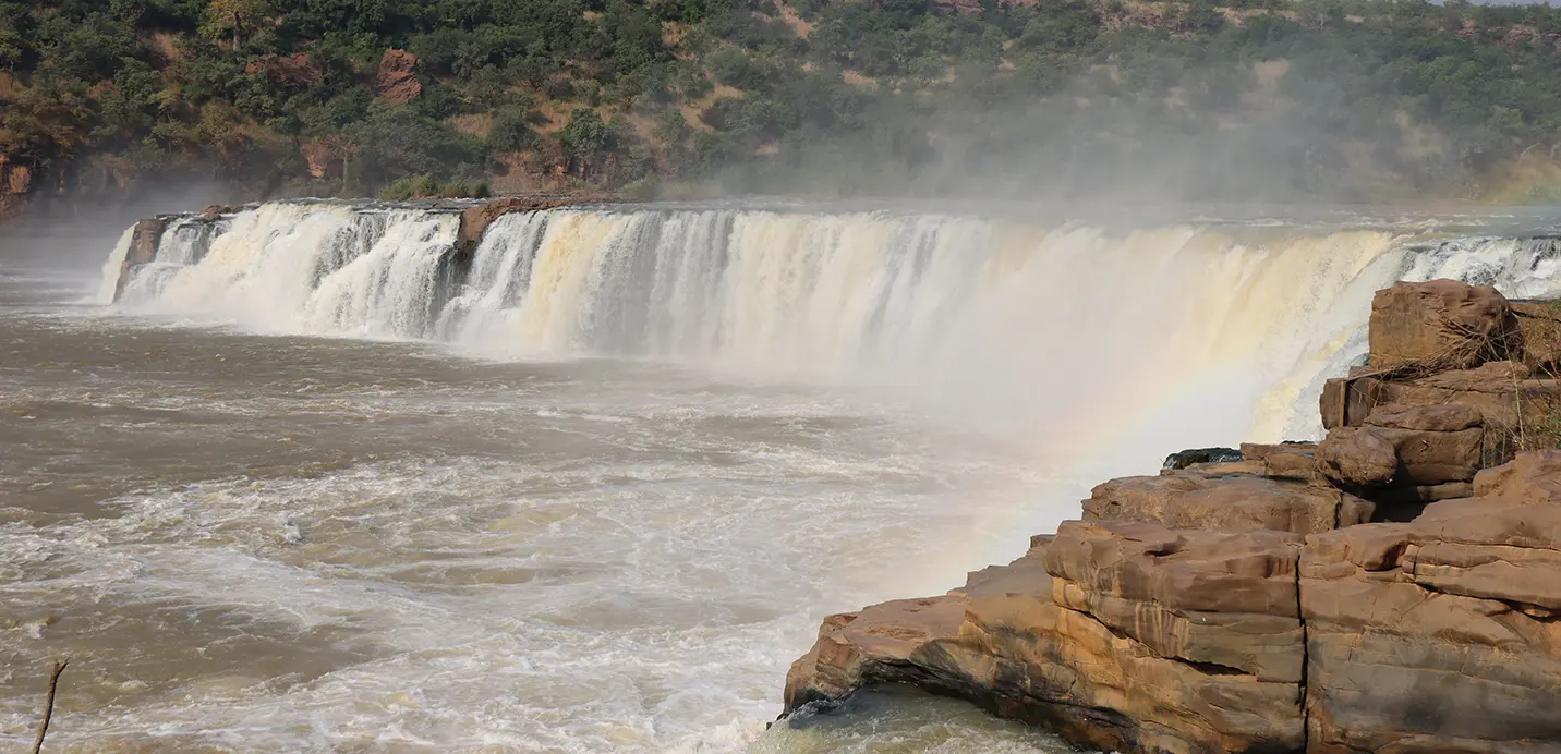 Chute d'eau puissante sur le fleuve, bordée de rochers ocre, dans la région de Kayes